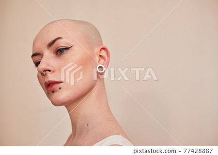 Serious female with blonde short hair and nude makeup looking away Serious female with blonde short hair and nude makeup looking away 77428887