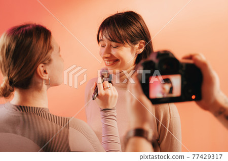 Woman laughing while stylist checking her makeup during the shooting 77429317