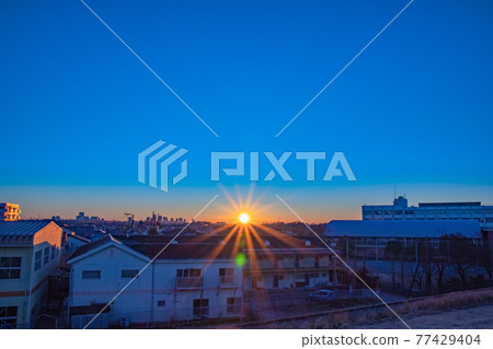 Sunrise climbing from the back of a residential area 77429404