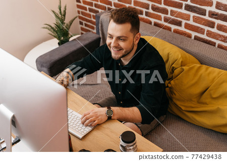 Photographer sitting at his workplace and smiling while watching captured photos 77429438