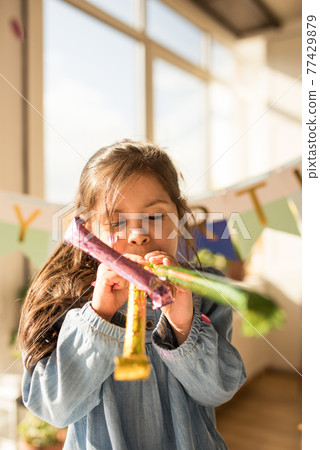 Girl blowing at the pipe at her birthday while playing and having fun at the kitchen 77429879