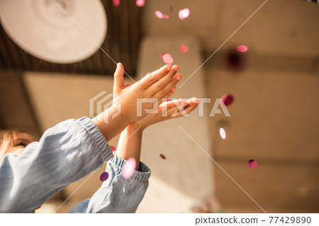 Girl enjoying of her birthday while stretching hands and catches confetti 77429890