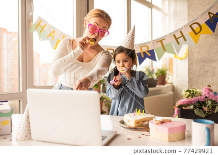 Mother celebrating birthday of her little daughter while speaking with friends Mother celebrating birthday of her little daughter while speaking with friends 77429921