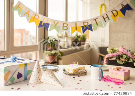 Birthday party table with birthday cake with candles, balloons and colored decor 77429954