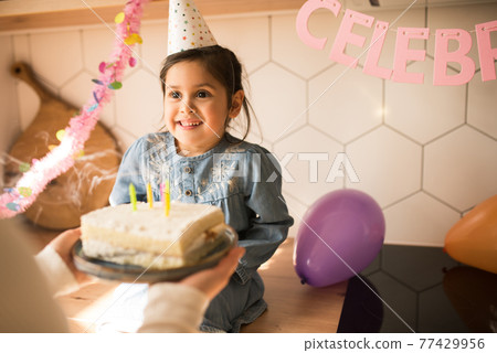 Girl looking at her mother after blowing candles at her birthday cake 77429956