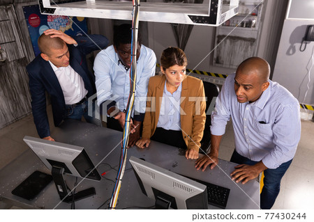 Four friends solving puzzles in quest room 77430244