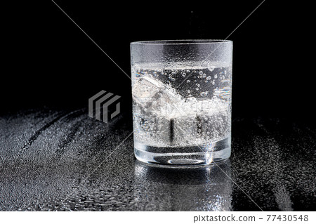Glass of Soda or Coctail with steel cooling cubes on dark glass background 77430548