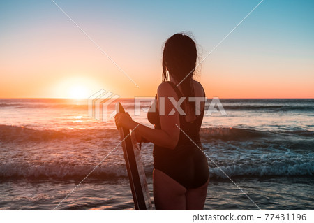 Woman with bodyboard entering the ocean Woman with bodyboard entering the ocean 77431196