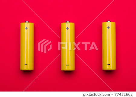 Yellow AA alkaline batteries on red background Yellow AA alkaline batteries on red background 77431662