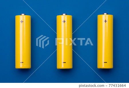 Yellow AA alkaline batteries on blue background Yellow AA alkaline batteries on blue background 77431664