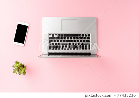 Overhead shot of laptop, mobile phone and green flower on pink desktop. Workplace concept. Flat lay Overhead shot of laptop, mobile phone and green flower on pink desktop. Workplace concept. Flat lay 77433230