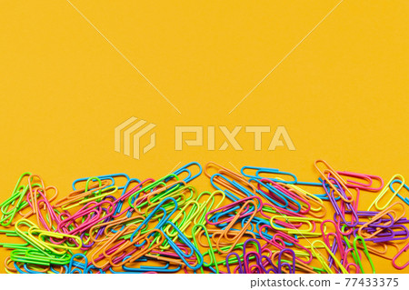 multicolored paper clips lie on a yellow background, with copy space, a bunch of paper clips multicolored paper clips lie on a yellow background, with copy space, a bunch of paper clips 77433375
