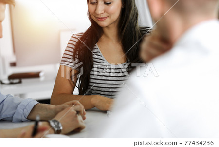 Group of business people discussing questions at meeting. Portrait of casual dressed businesswoman happy smiling to her colleagues 77434236