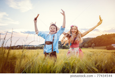 Happy Mother and Son in Bavaria jumping in a meadow 77434544