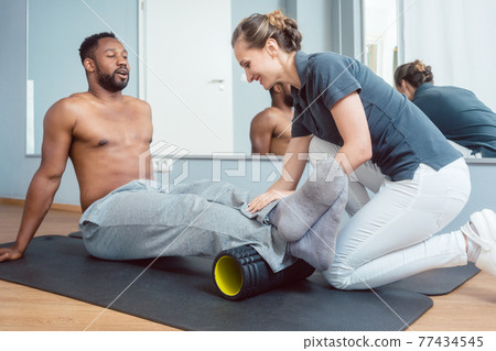 Young man doing fascia training with roll 77434545