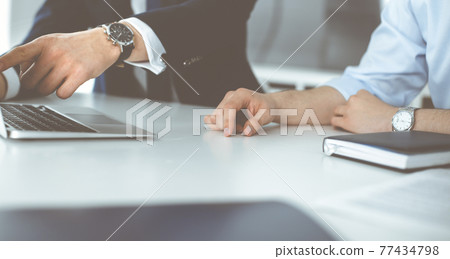 Unknown business people using laptop computer at the desk in modern office. Businessman or male entrepreneur is working with his colleague. Teamwork and partnership concept 77434798