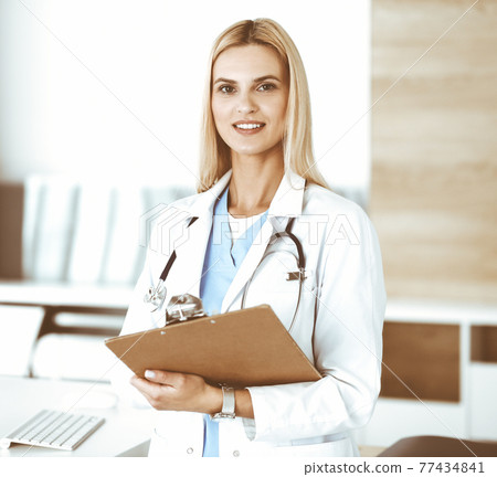 Doctor woman at work in hospital controls medication history records and exam results while using clipboard. Medicine and healthcare concept 77434841