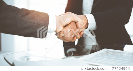 Unknown diverse business people are shaking hands finishing contract signing in sunny office, close-up. Business handshake concept Unknown diverse business people are shaking hands finishing contract signing in sunny office, close-up. Business handshake concept 77434944
