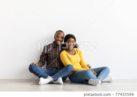 Portrait Of Happy Black Couple Sitting On Floor In Empty Flat Portrait Of Happy Black Couple Sitting On Floor In Empty Flat 77435599