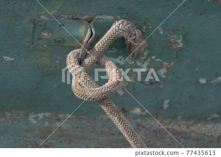 Sailing boat tied with a rope tied in a sea knot Sailing boat tied with a rope tied in a sea knot 77435613