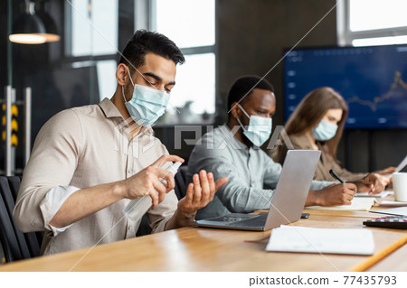 International workers wearing medical masks using sanitizer 77435793