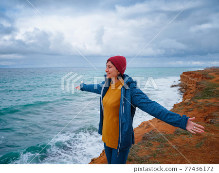 Hipster woman traveler in yellow sweater and red hat enjoying fresh air 77436172