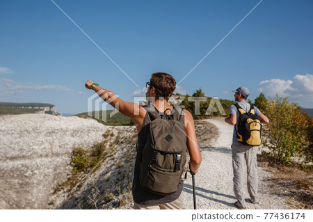 Two Hikers with Backpacks and other climbing Gear staying on top Two Hikers with Backpacks and other climbing Gear staying on top 77436174