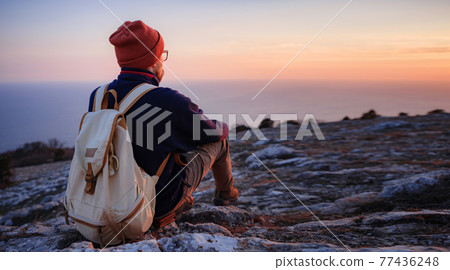 A man on top of a cliff in the spring mountains at sunset and enjoying the view of nature A man on top of a cliff in the spring mountains at sunset and enjoying the view of nature 77436248