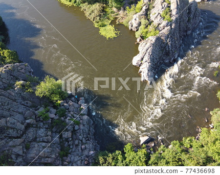 A bend of the Southern Bug river called Integral from a bird's eye view. A picturesque river among the rocky terrain. 77436698