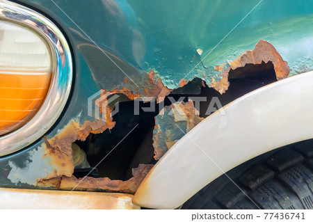 metal corrosion on a car fender close up, rust hole 77436741