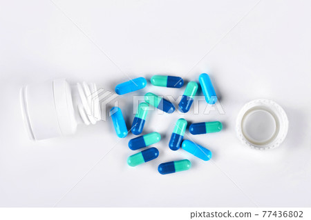 Blue medical capsules and white bottle. 77436802