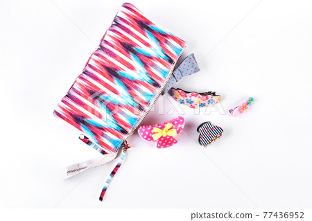 Hair clips next to opened cosmetics bag. 77436952