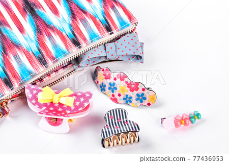 Hair clips next to patterned bag. 77436953