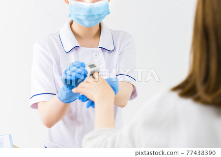 A nurse measuring saturation with a pulse oximeter 77438390