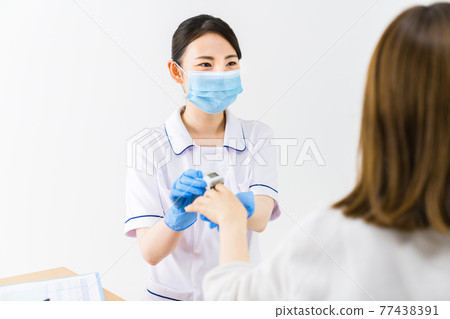 A nurse measuring saturation with a pulse oximeter 77438391
