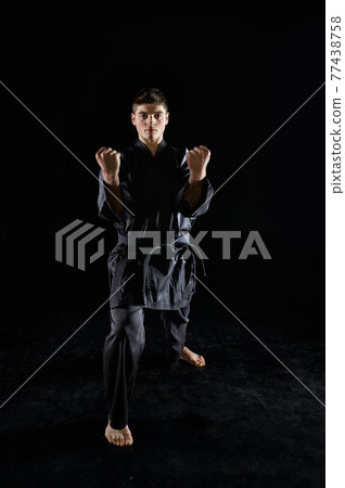 Male karate fighter in black kimono, front view Male karate fighter in black kimono, front view 77438758