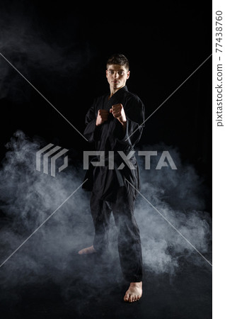 Male karate fighter in black kimono, combat stance 77438760