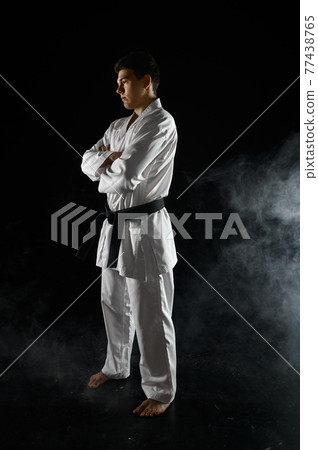 Male karate fighter in white kimono, combat stance 77438765