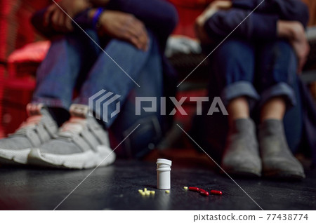 Drug addicts sitting on the floor in den 77438774