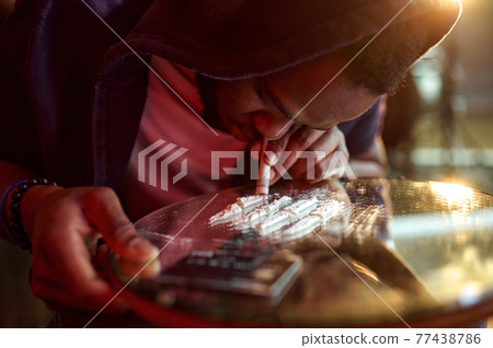 Drug addict man takes a dose of powder Drug addict man takes a dose of powder 77438786