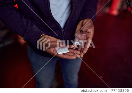 Drug addict man holds package of pills and powder Drug addict man holds package of pills and powder 77438806