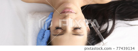 Doctor in gloves doing facial massage with darsonval Doctor in gloves doing facial massage with darsonval 77439134