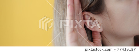Young hard of hearing woman holding her hand near ear 77439187