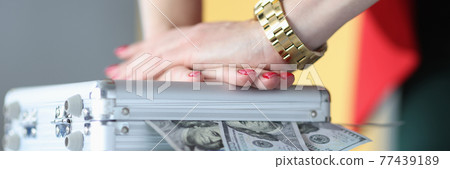 Female hands closing metal suitcase with dollar bills closeup 77439189