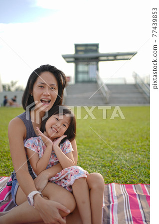 Asian mother and daughter enjoying outdoors picnic Asian mother and daughter enjoying outdoors picnic 77439853