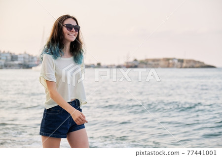 Beautiful teenager girl in sunglasses with dyed blue hair on sea beach, copy space Beautiful teenager girl in sunglasses with dyed blue hair on sea beach, copy space 77441001