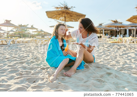 Mom applying sunscreen lotion to daughter's skin Mom applying sunscreen lotion to daughter's skin 77441065