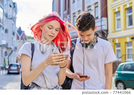 Couple of trending teenagers friends with smartphone on city street 77441066