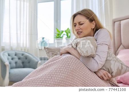 Sad stressful middle-aged woman sitting at home in bed under blanket 77441108