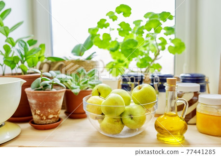 Home pantry, plants in pots, honey, chocolate paste, apples, bottle of olive oil 77441285